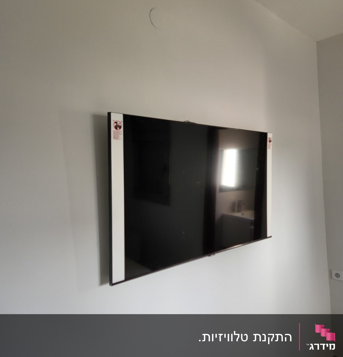 טלוויזיה מותקנת על קיר לבן עם תושבת